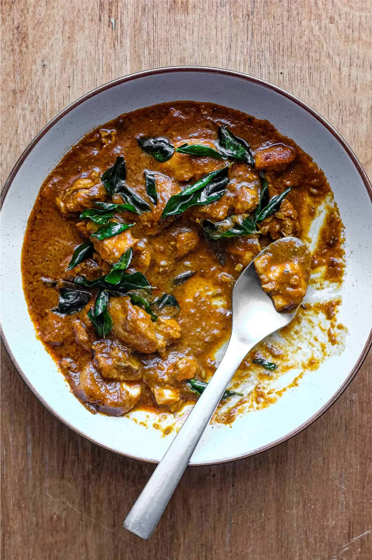 A bowl of Chicken Madras Curry scattered with fried curry leaves