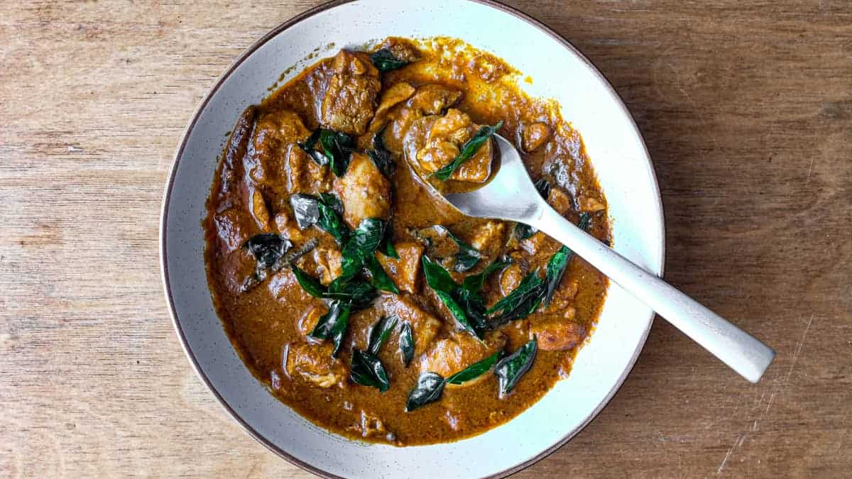 A bowl of Chicken Madras Curry scattered with fried curry leaves