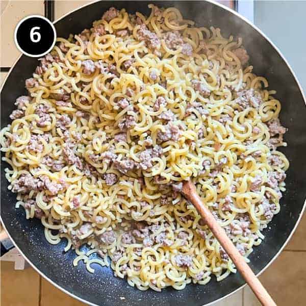 A pan and wooden spoon of Gramigna pasta with sausage