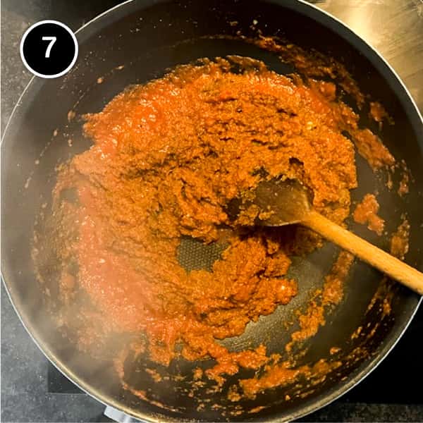 Tomato passata stirred into a curry sauce in a pan