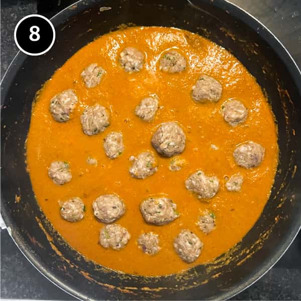 Raw meatballs dropped into a pan of curry sauce for cooking.