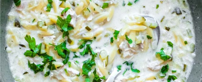 A bowl of Greek lemon orzo soup with chicken with a spoon