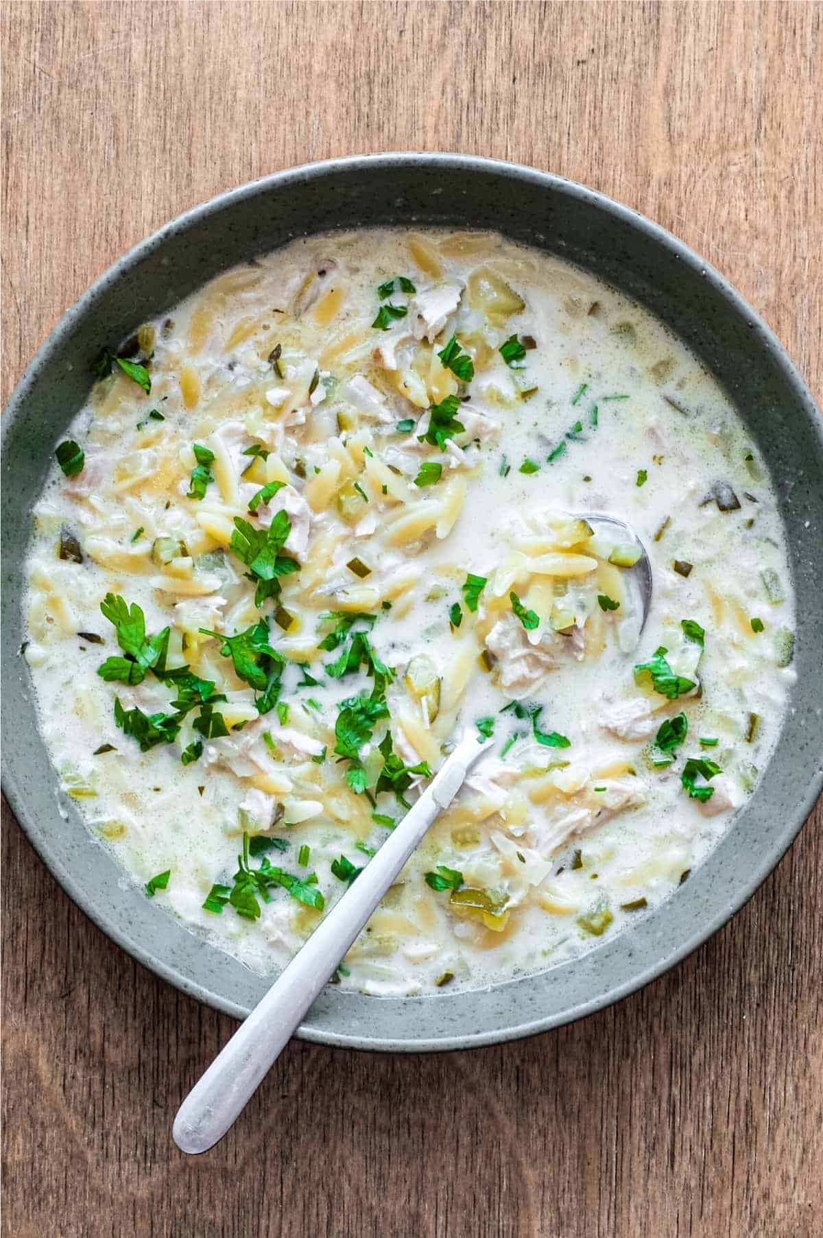 A bowl of Greek lemon orzo soup with chicken with a spoon
