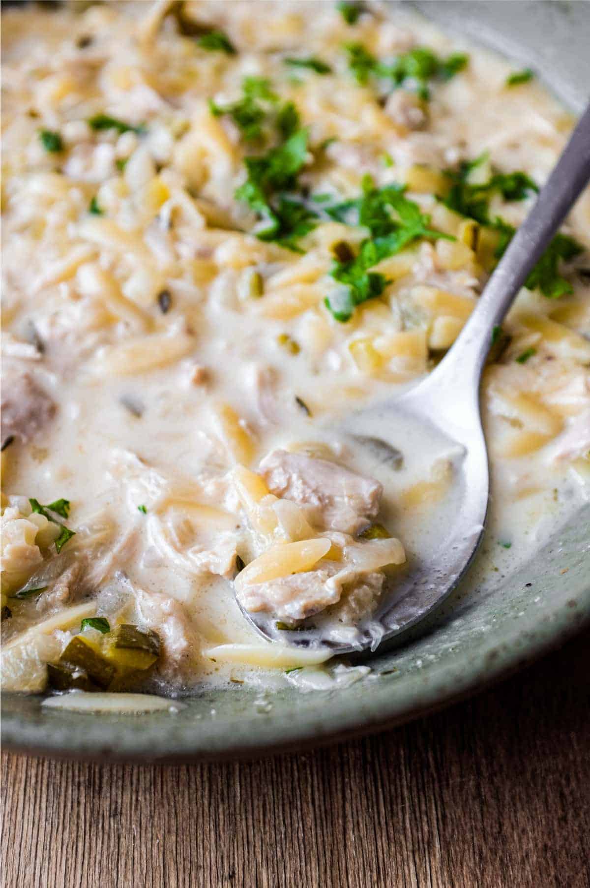 A bowl of Greek lemon orzo soup with chicken with a spoon