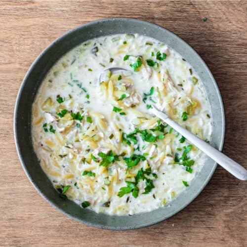 A bowl of Greek lemon orzo soup with chicken with a spoon