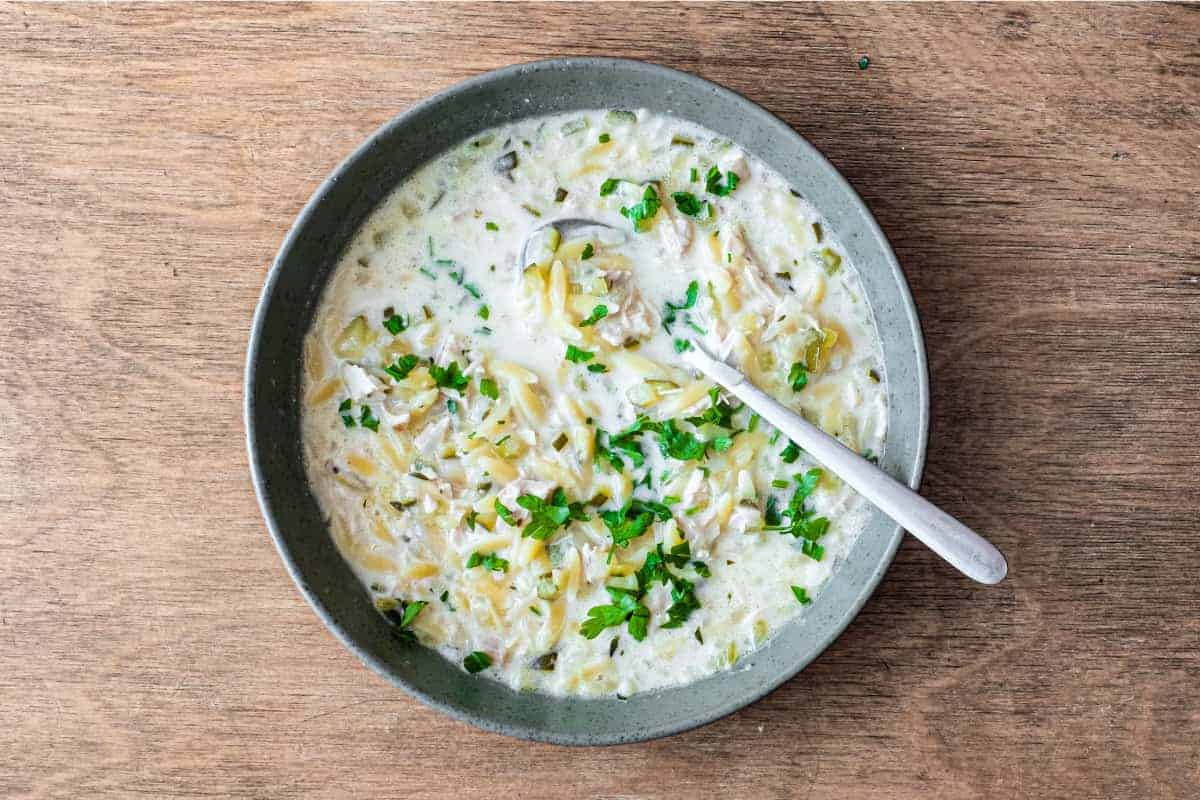 A bowl of Greek lemon orzo soup with chicken with a spoon