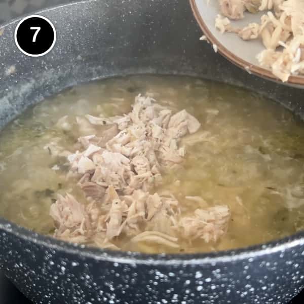 Chopped cooked chicken thighs are returned to the pan of soup.