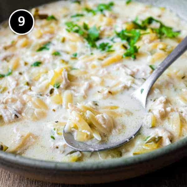 A bowl of Greek lemon orzo soup with chicken with a spoon