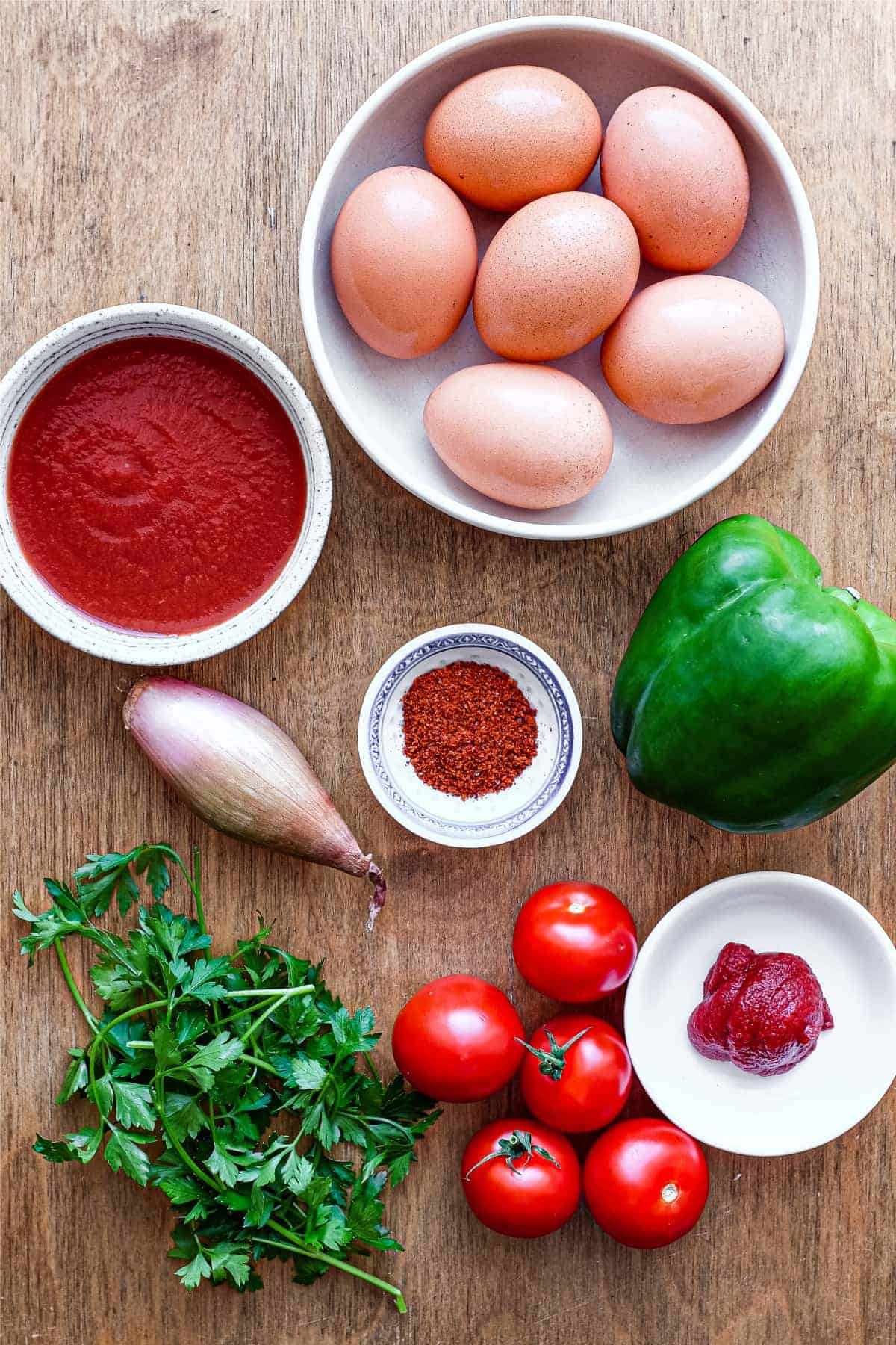 The ingredients for Turkish menemen: eggs, tomatoes, tomato concentrate, tomato passata, green bell pepper, parsley, shallot and Aleppo pepper