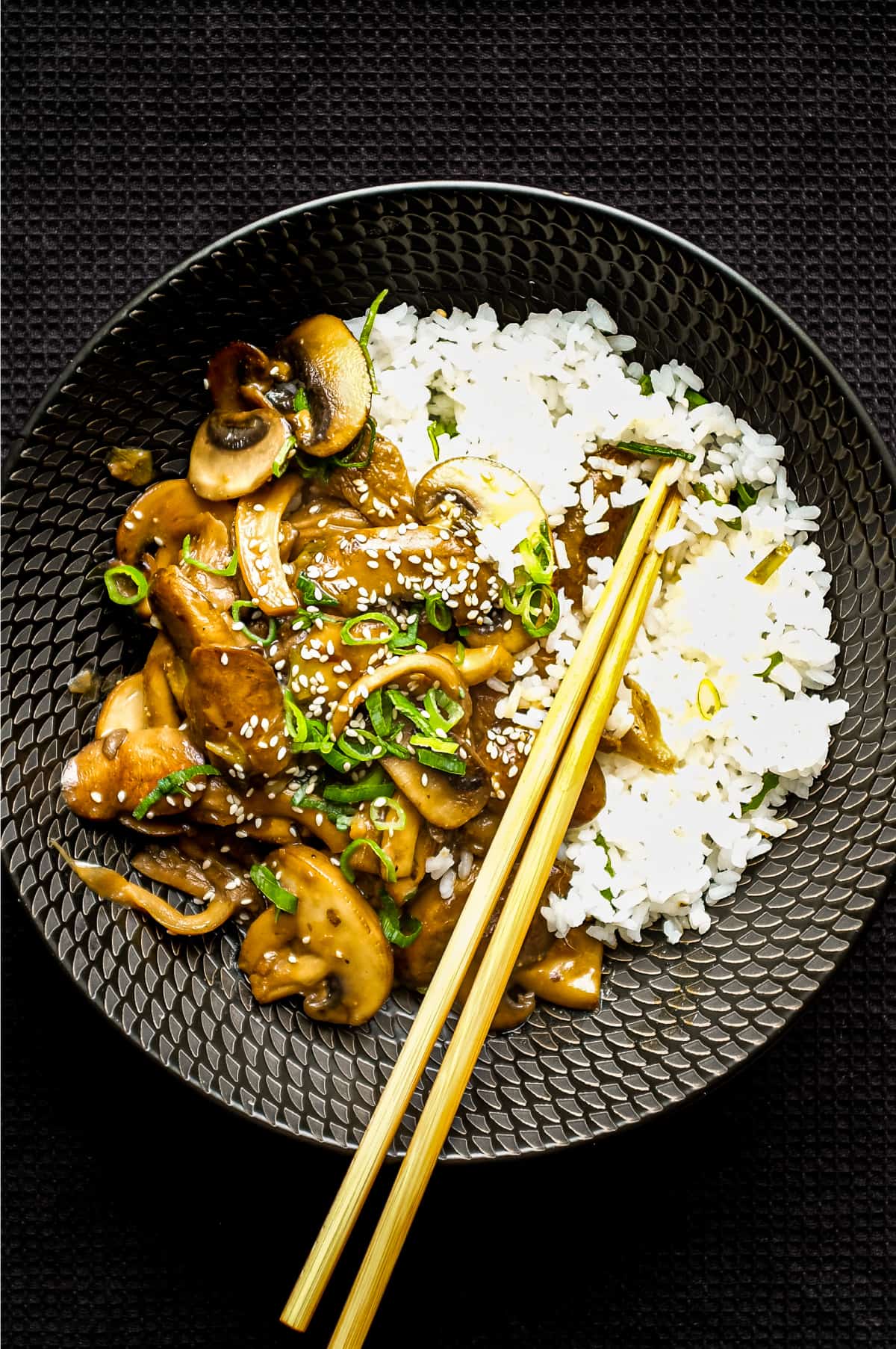 A bowl of rice topped with sautéed miso mushrooms. Chopsticks sit alongside the bowl.