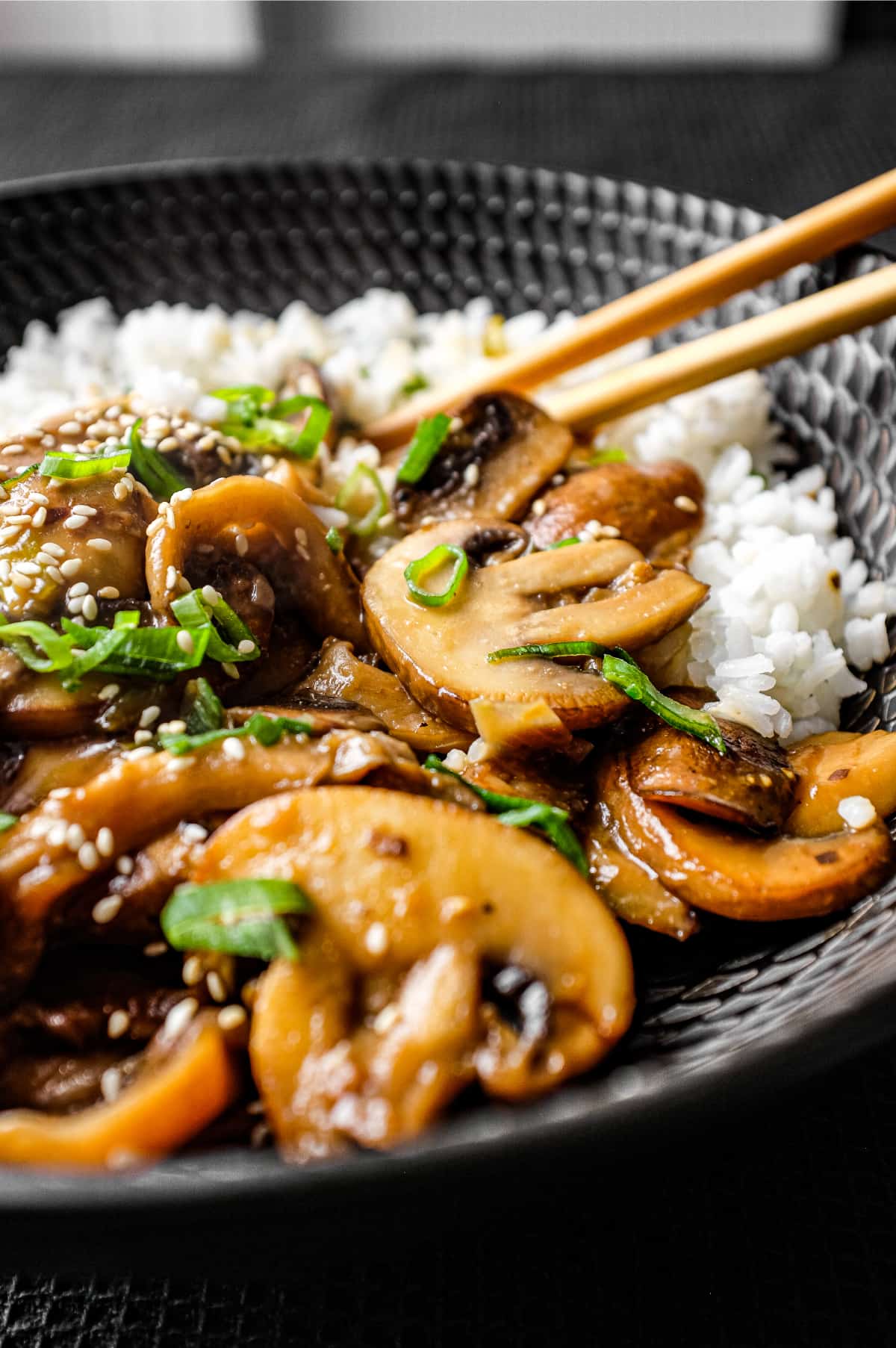 A bowl of rice topped with sautéed miso mushrooms. Chopsticks sit alongside the bowl.
