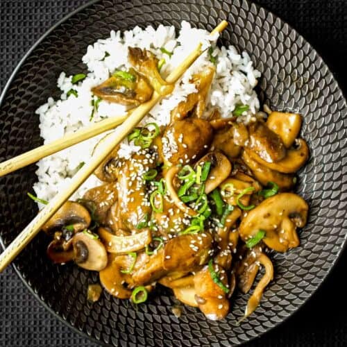 A bowl of rice topped with sautéed miso mushrooms. Chopsticks sit alongside the bowl.