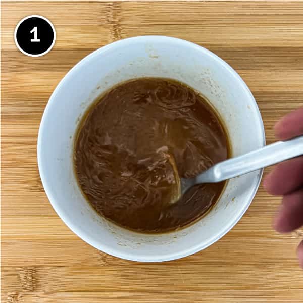A mixture of soy sauce, miso, sesame oil, vinegar and more in a small bowl.