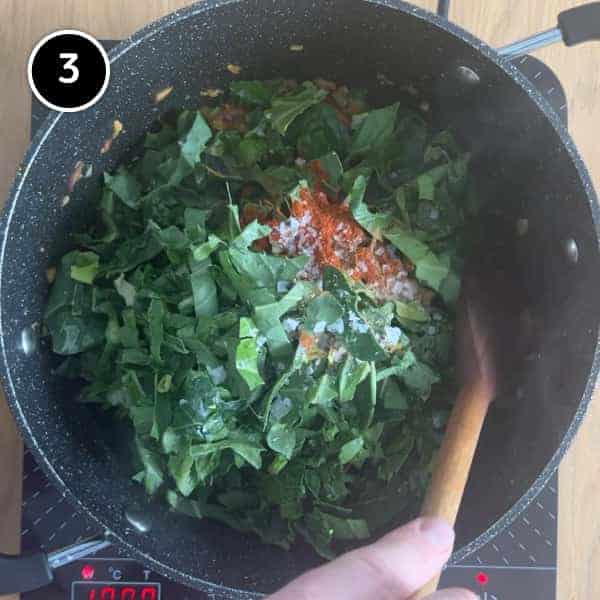 Kale and cabbage leaves being added to a large pot for Spanish bean stew.