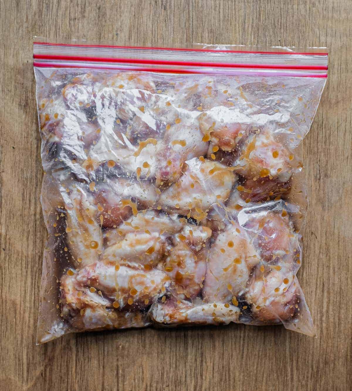 A plastic bag holding chicken wings in a Chinese marinade