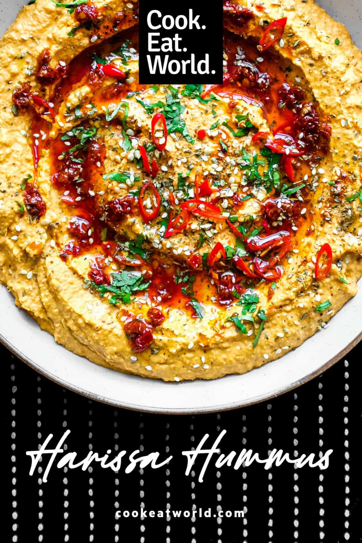 A bowl of Harissa Hummus garnished with chillies, chilli oil, zaatar and fresh cilantro.