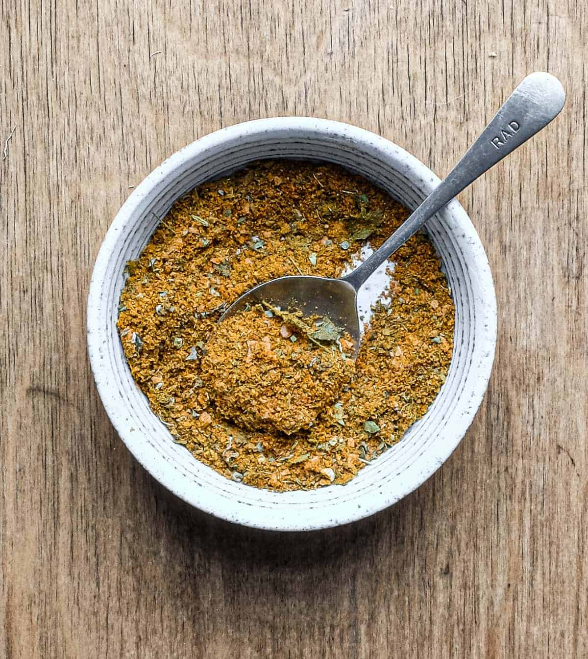 A small bowl with a spoon containing Indian gunpowder spice mix.