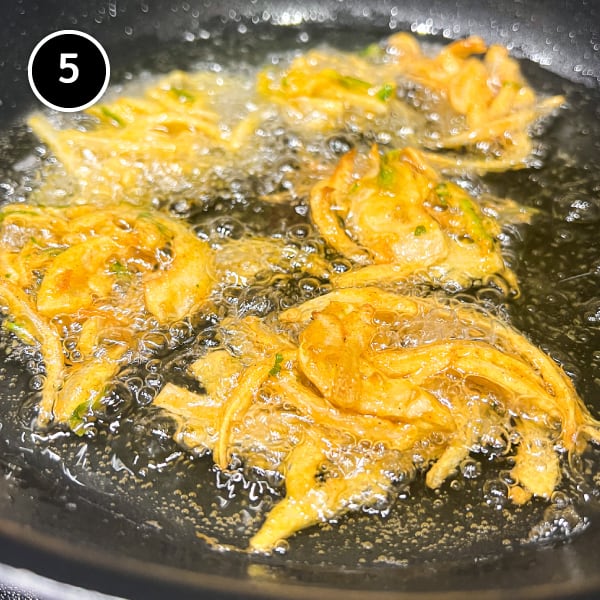 Four onion pakoda frying in oil in a pan
