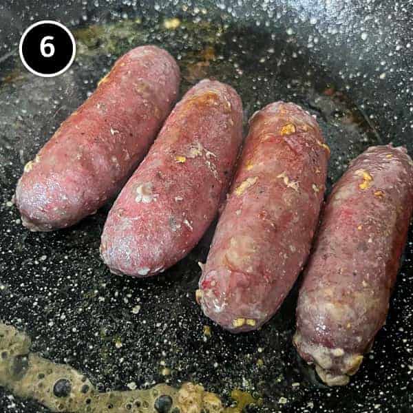 Italian Sausage and Lentils | cookeatworld.com Four Italian sausages frying in a pan.