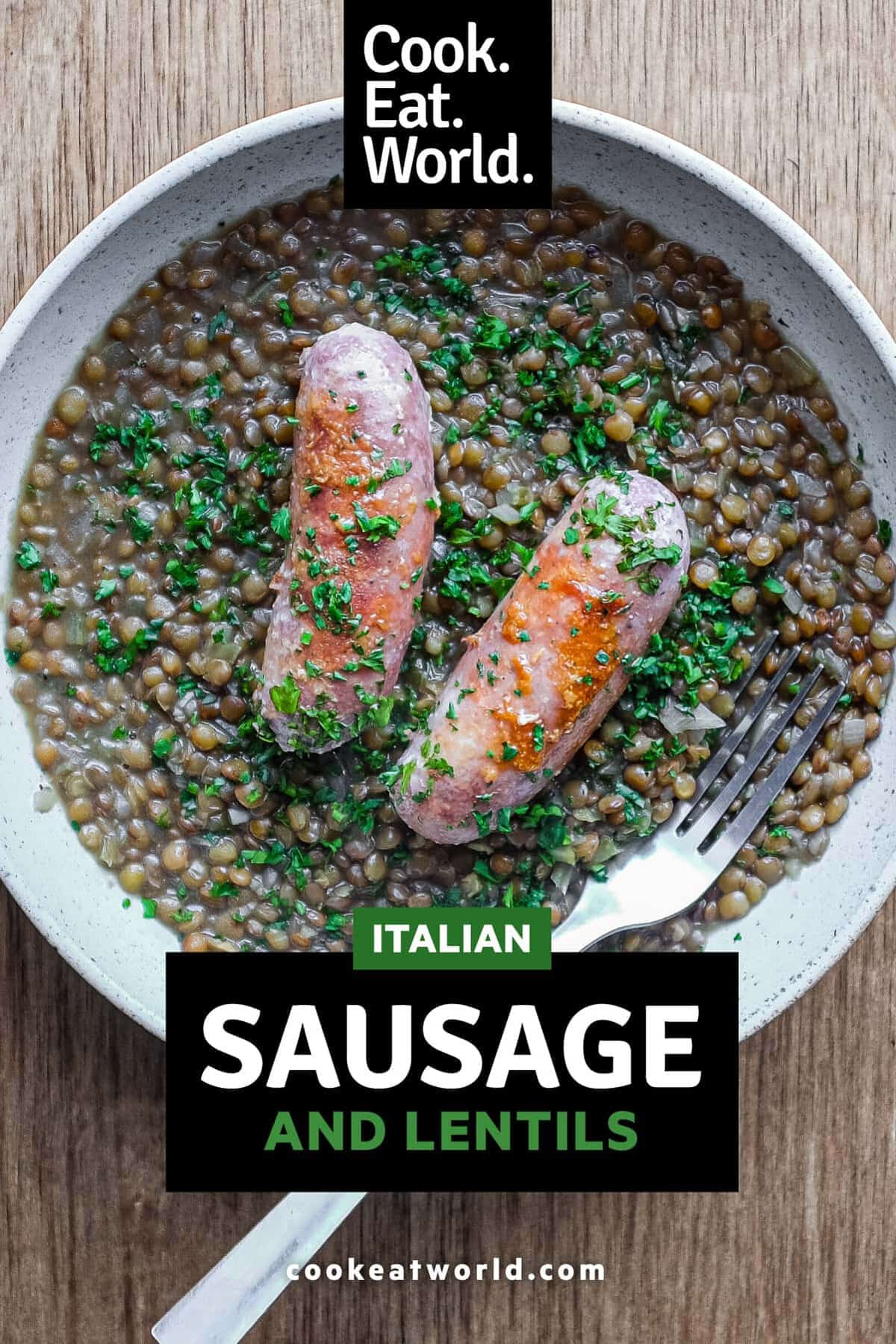 A shallow bowl has a layer of creamy lentils, topped with two Italian pork and fennel sausages. The dish is garnished with fresh parsley.