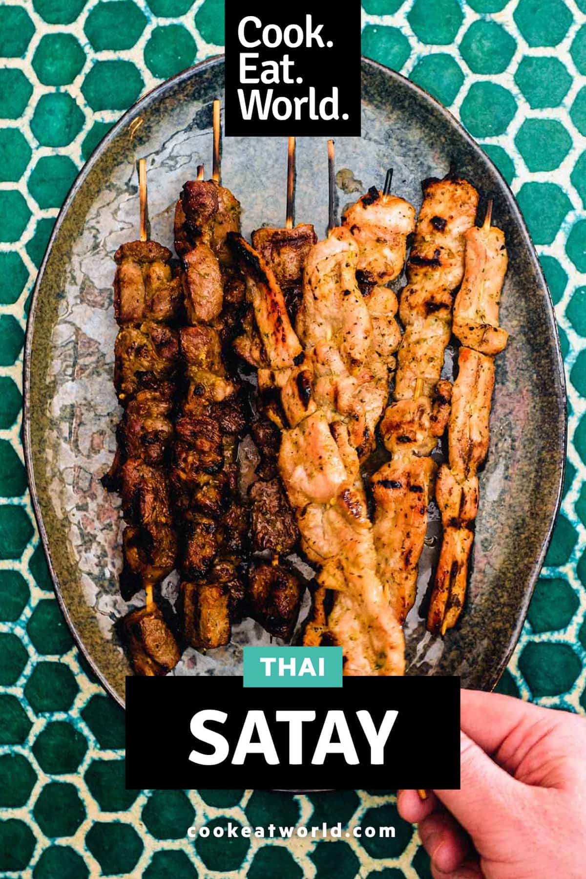 Beef and Pork satay skewers sit on a serving platter on a green batik background.