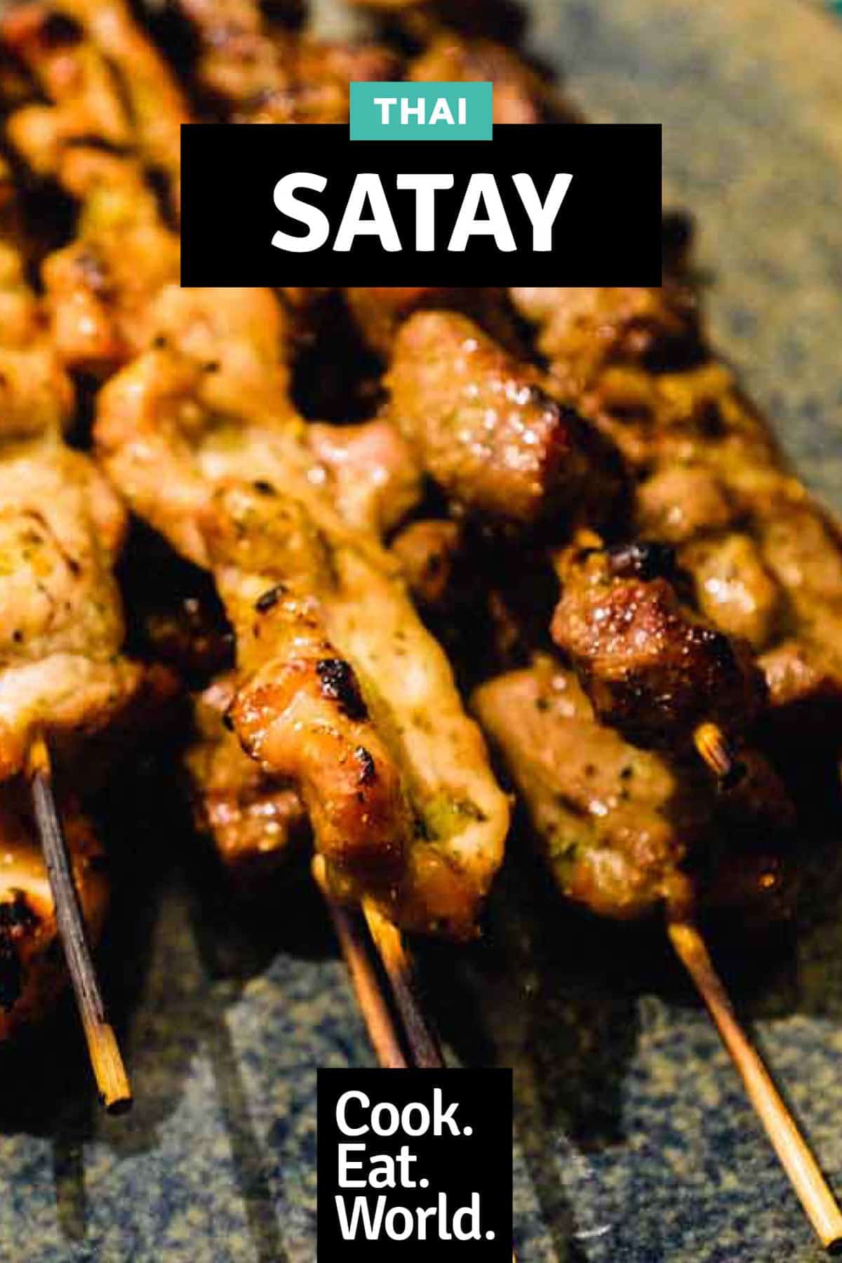 Beef and Pork satay skewers sit on a serving platter on a green batik background.