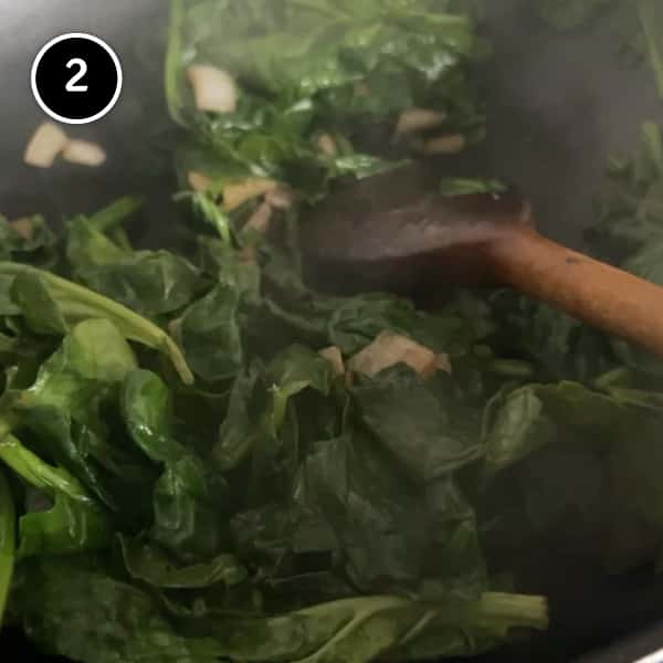 Wilting spinach in a pan with soft onion.