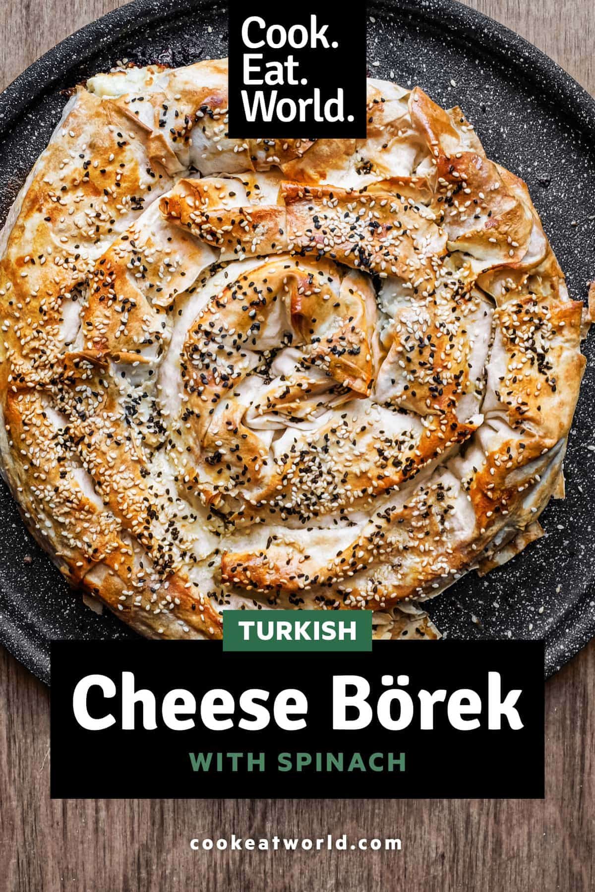 A coiled Turkish Börek on a baking sheet, scattered with sesame and nigella seeds.