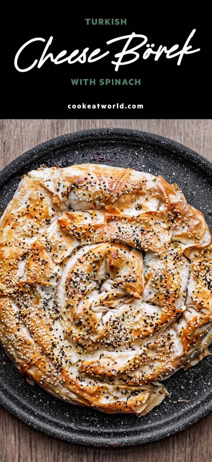 A coiled Turkish Börek on a baking sheet, scattered with sesame and nigella seeds.