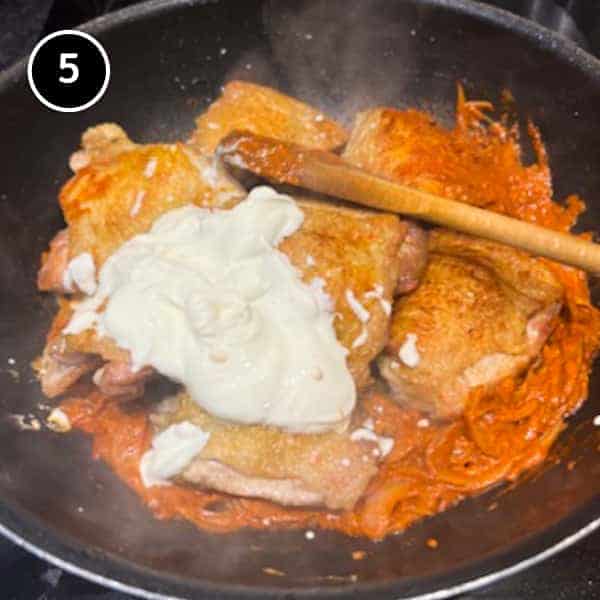 Adding the chicken and sour cream to a creamy sauce made from chipotle peppers