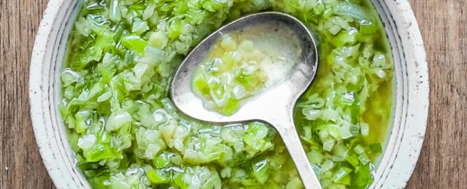 A small bowl of Chinese Ginger Scallion Sauce with a small serving spoon