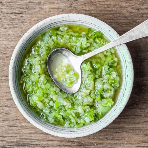 A small bowl of Chinese Ginger Scallion Sauce with a small serving spoon