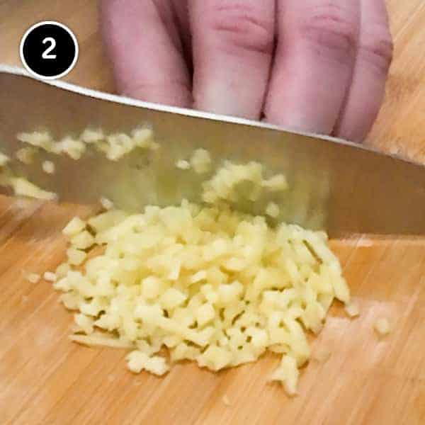 Chopping fresh ginger finely on a chopping board