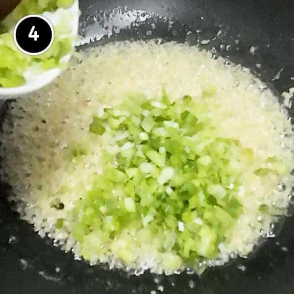 Adding finely chopped scallions to frying fresh ginger in a wok.