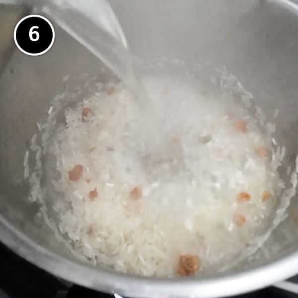 Pouring over chicken broth into a pan of rice.