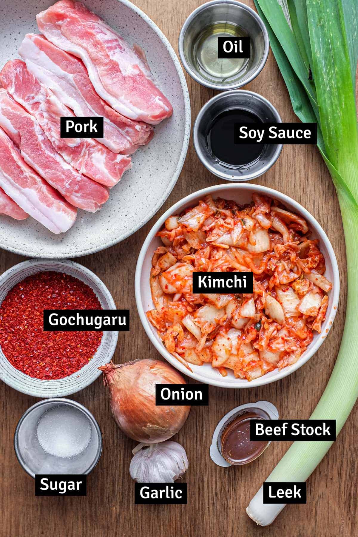 The ingredients for Korean kimchi pork stew: kimchi, pork belly, gochugaru chilli flakes, leek and more.