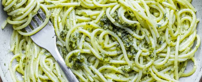 A fork wraps around spaghetti with Pistachio Pesto in a large bowl