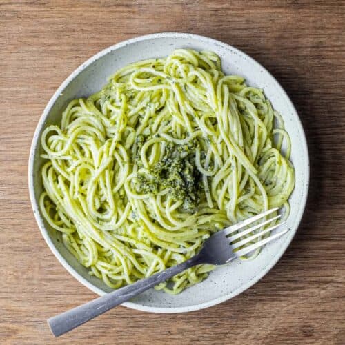 A fork wraps around spaghetti with Pistachio Pesto in a large bowl
