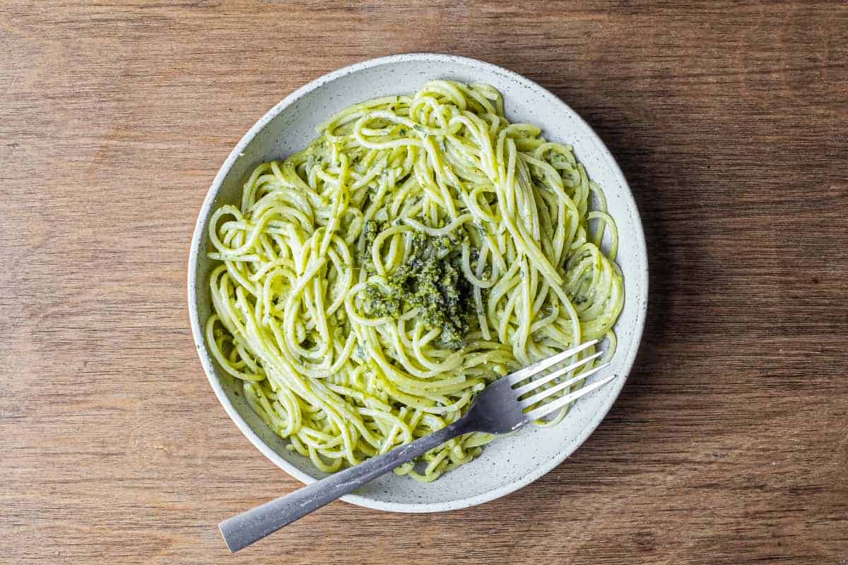 A fork wraps around spaghetti with Pistachio Pesto in a large bowl