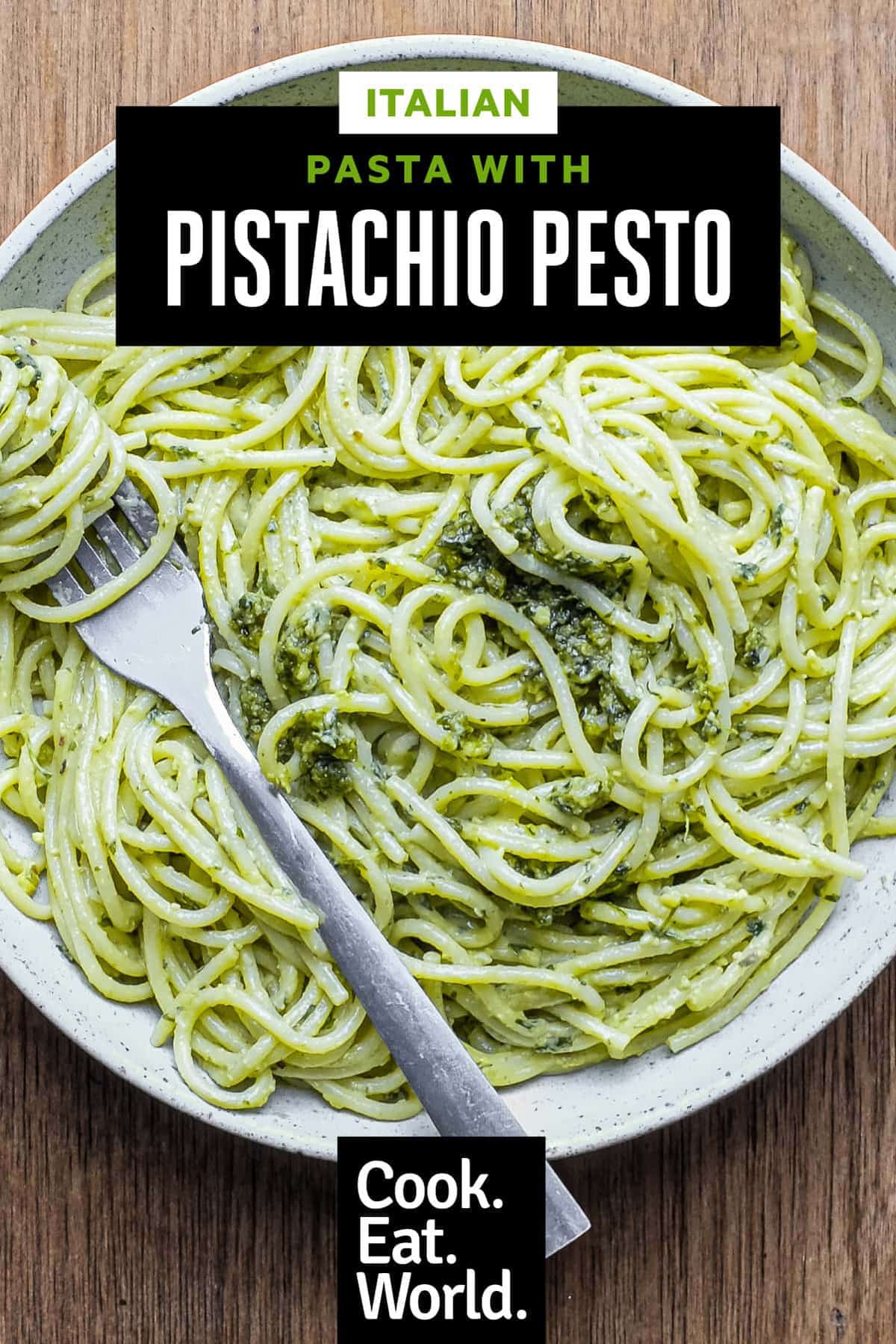 A fork wraps around spaghetti with Pistachio Pesto in a large bowl