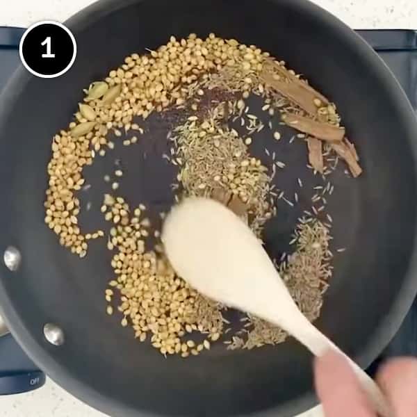 Spices being dry fried in a small frying pan to make a curry powder for beef balti