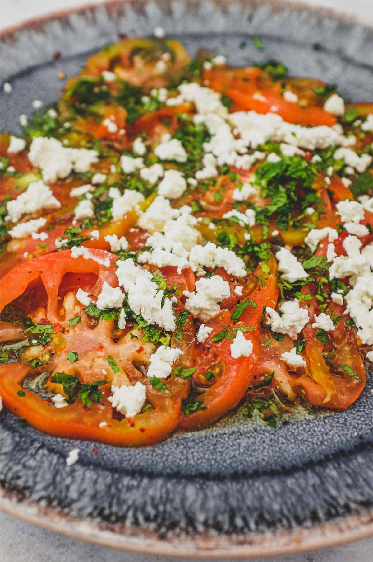 Tomatoes dressed in vinegar and oil with feta cheese and chopped mint