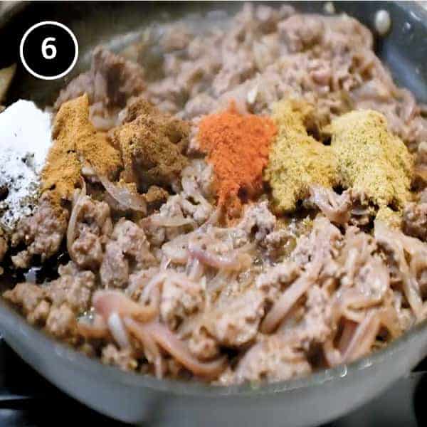 Adding ground spices to ground lamb in a small pan