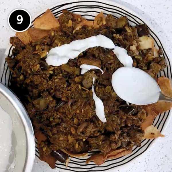 Arranging the lamb fatteh with flatbreads, spiced lamb and eggplant and drizzling yoghurt sauce on a large platter.