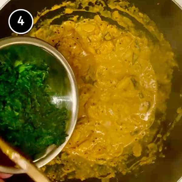 Adding spinach to a shrimp curry in a pan