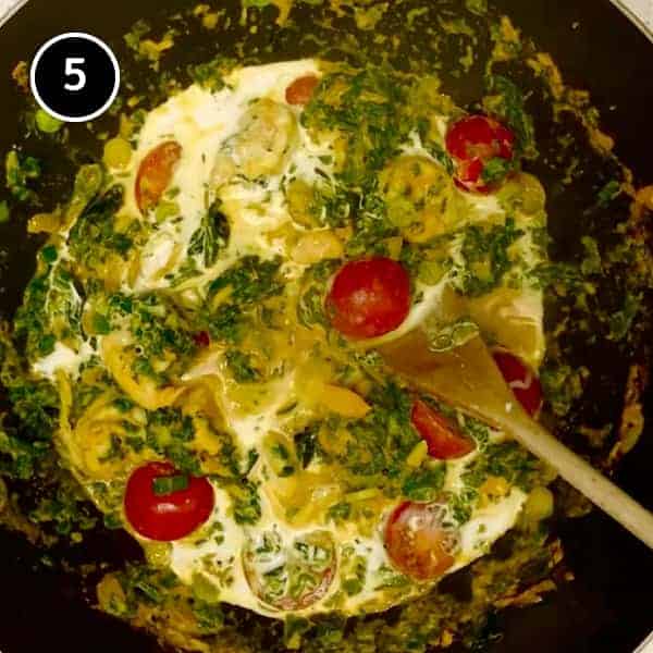 Adding tomatoes and coconut milk to a pan of coconut shrimp curry - Jheenga Palak.