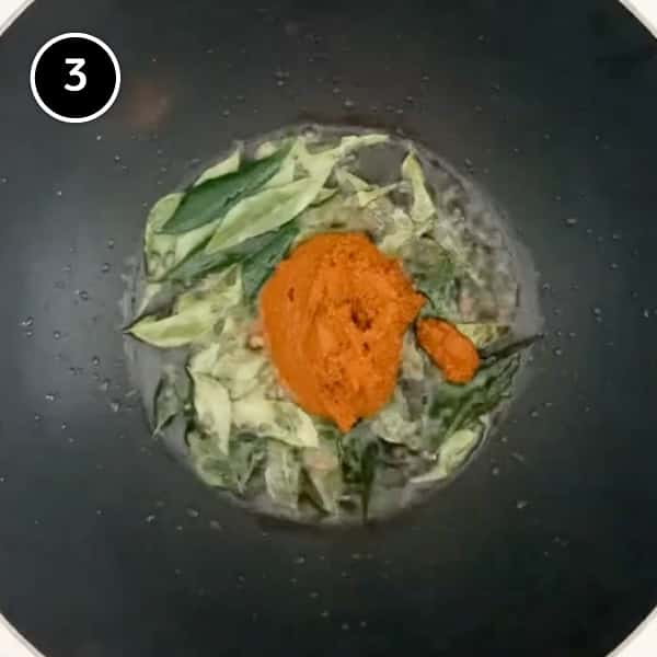 frying fresh curry leaves with a curry paste in a wok