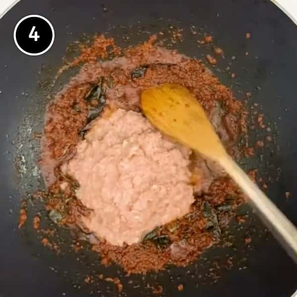 Adding onion paste to a frying curry paste in a wok