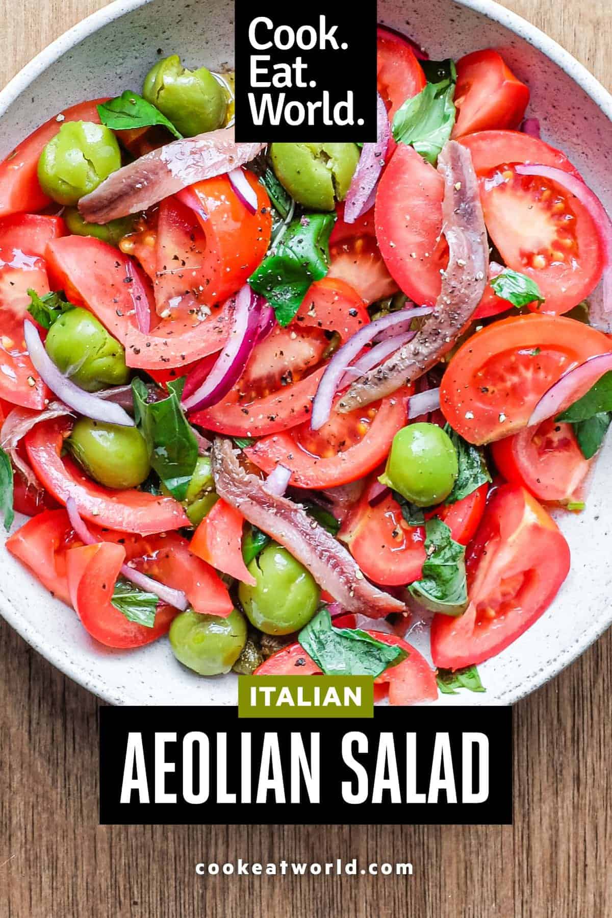 A bowl of Tomato salad with olives, capers, red onion, anchovies and fresh basil.