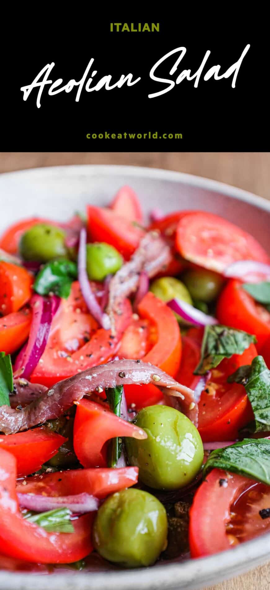 A bowl of Tomato salad with olives, capers, red onion, anchovies and fresh basil.